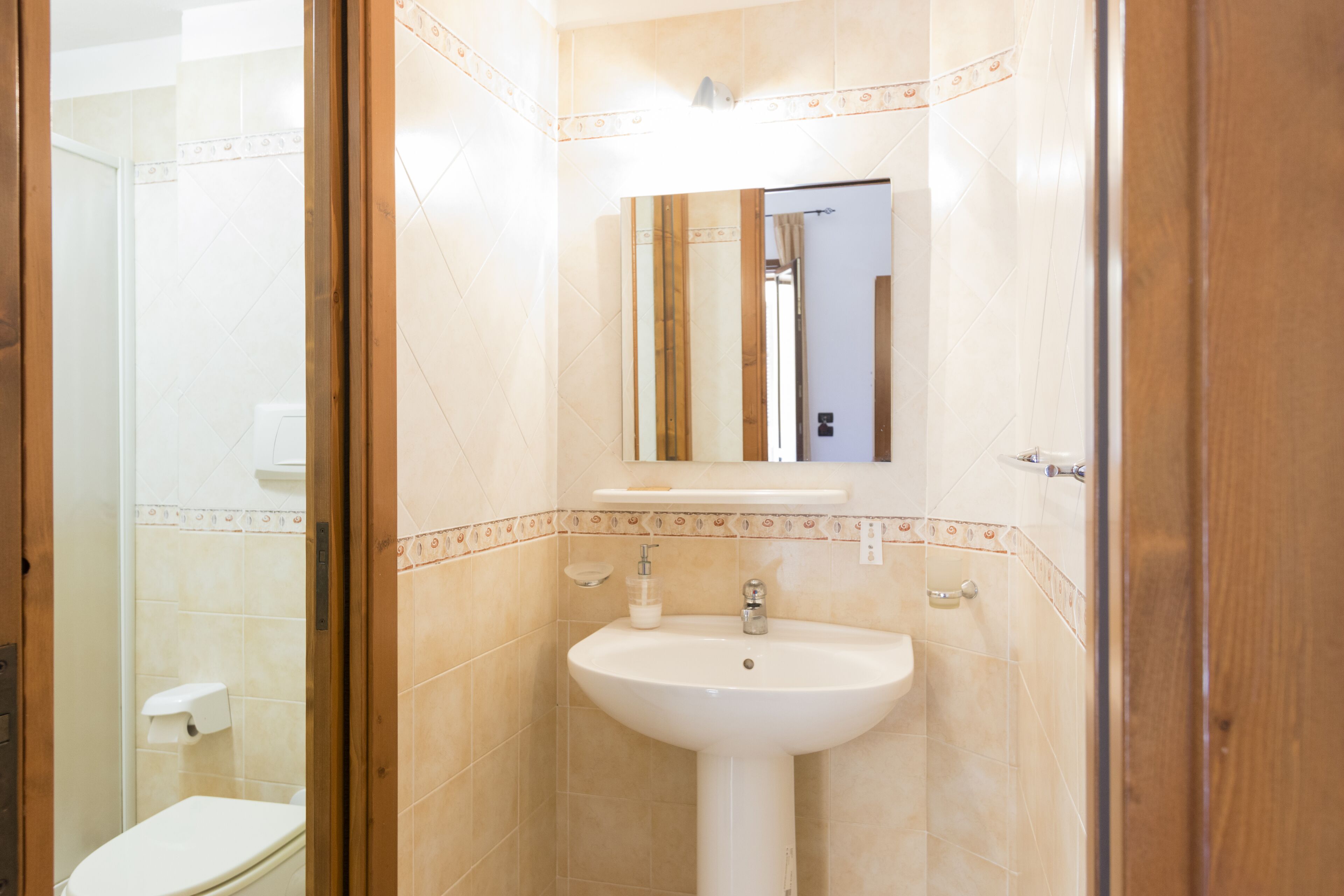 A bathroom with a white sink, mirror, and toilet.