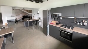 A modern kitchen with a central island, stainless steel appliances, and a staircase leading to a living area. - MAISON DE VACANCES près de Thermes de Bucarest & Otopeni Airport (Balotesti)