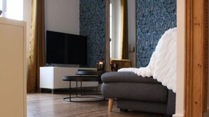 Una sala de estar moderna con piso de madera, un sofá gris, un televisor de pantalla plana y un espejo grande.