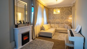 Ein Wohnzimmer mit Kamin, Sofa, Klavier und einem großen Spiegel.