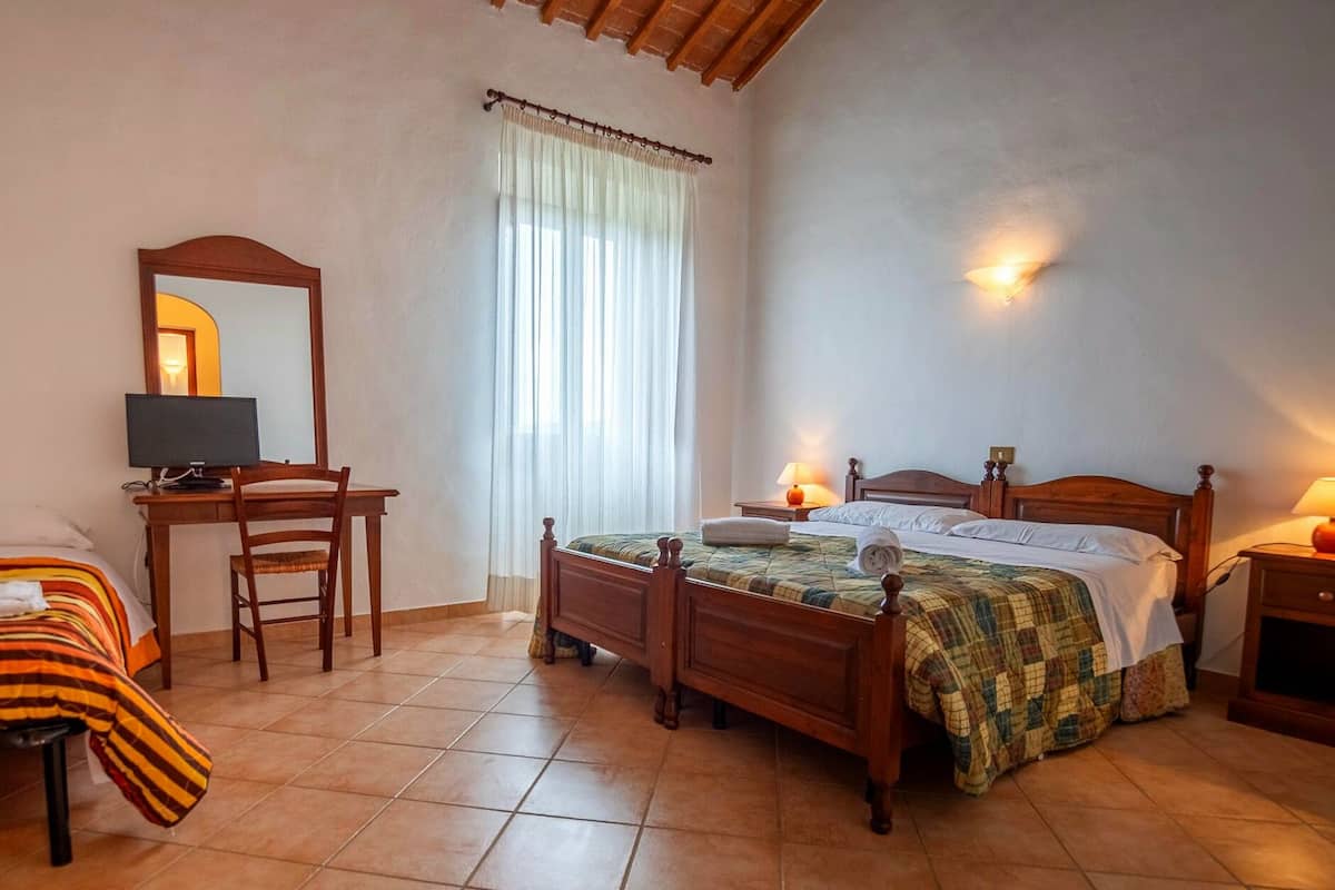 Ein Schlafzimmer mit einem hölzernen Bett, einem Schreibtisch mit Stuhl, einem Fernseher und zwei Nachttischlampen.