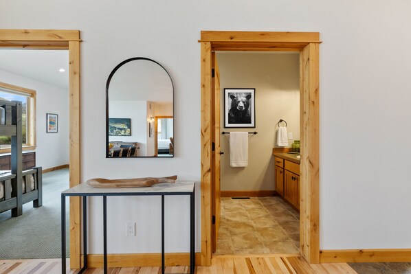 A wooden-framed doorway leading to a bathroom with a sink and towel rack. - Caddis Shack on the Yellowstone River (Pray)