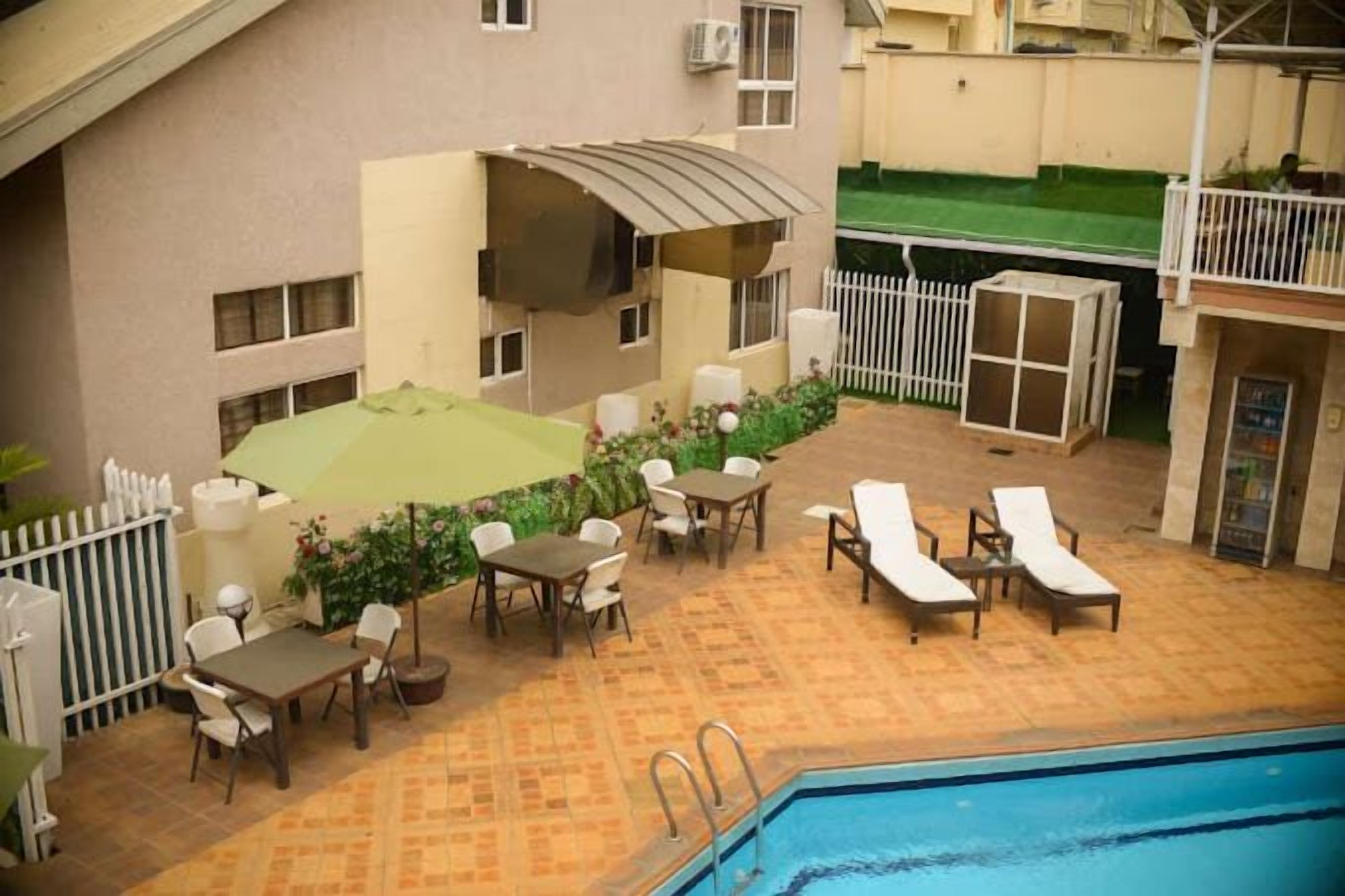Un área junto a la piscina con un espacio de estar cubierto, sillas de descanso y una piscina.