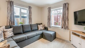 A modern living room with a grey sectional sofa, a flat-screen TV, and a white cabinet.
