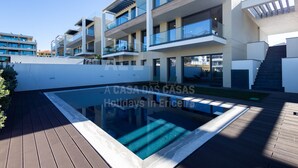 A modern multi-story building with balconies, a swimming pool, and a wooden deck. - Casa Mango by Acasadascasas (Mafra)