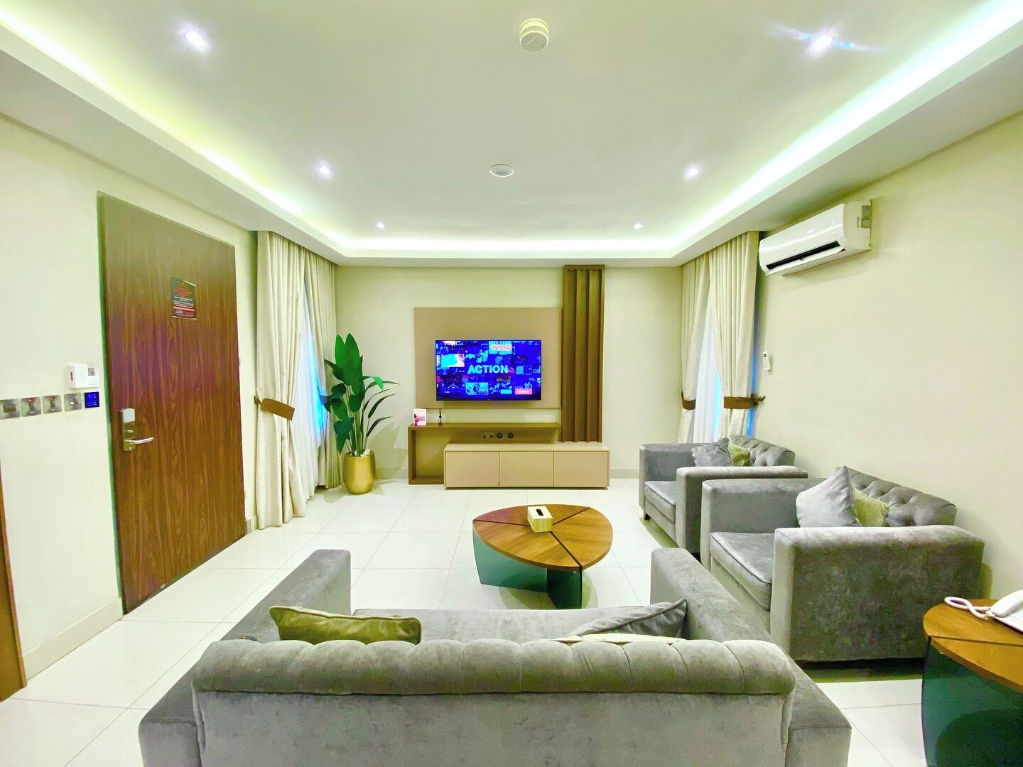 Una sala de estar moderna con una televisión de pantalla plana, sofás, una mesa de centro y un equipo de aire acondicionado.