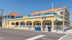 A yellow building with a balcony, a 'For Sale' sign, and a street sign for 'New Jersey Ave'.