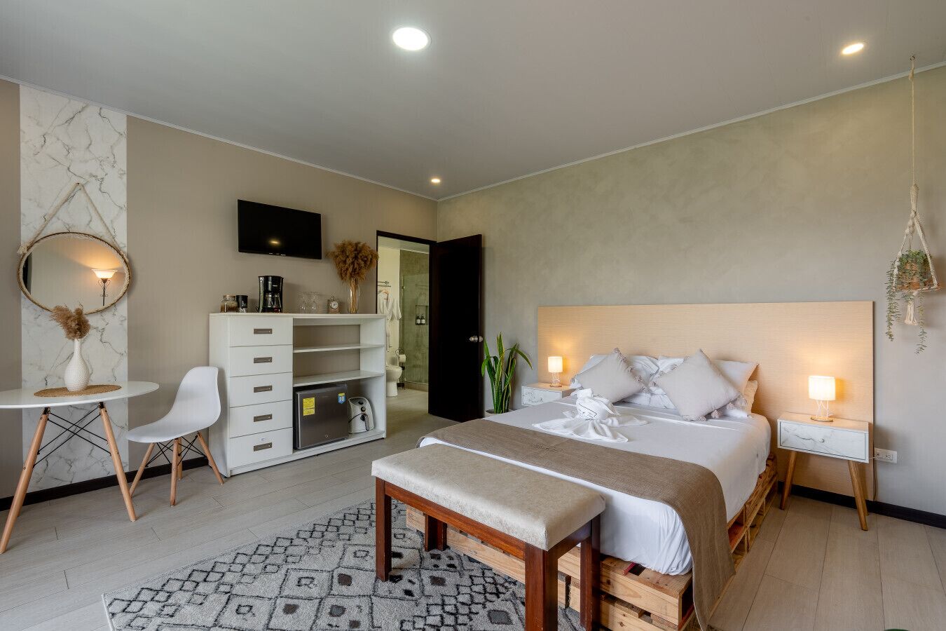 A modern bedroom with a bed, bedside tables, a desk, a chair, and a wardrobe.