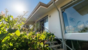 A modern building with large windows, a balcony, and a staircase leading to the entrance. - House of Turri: Suite | Views | Terrace | Jacuzzi (Turrialba)