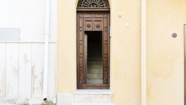 A building with a wooden door and a small window above it. - Visitsicilia Le Magnolie 4 (Castellammare del Golfo)