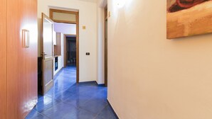 A hallway with wooden doors, a blue tiled floor, and a painting on the wall. - Visitsicilia Le Magnolie 4 (Castellammare del Golfo)