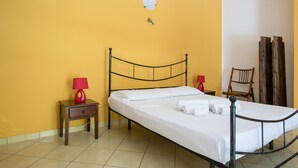 A single bed with a metal frame, two bedside tables with lamps, a wooden chair, and a wall-mounted light fixture. - Visitsicilia Le Magnolie 2 (Castellammare del Golfo)