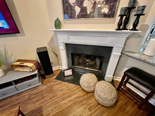 Una sala de estar con chimenea, un mapa del mundo en la pared y una mesita con un altavoz.