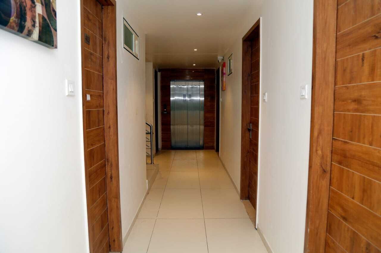 Un pasillo con paneles de madera en las paredes, piso de baldosas y un ascensor al final.