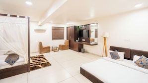 A modern hotel room with a bed, a sofa, a TV, and a small seating area. - Hotel Bhabha (Rajkot)