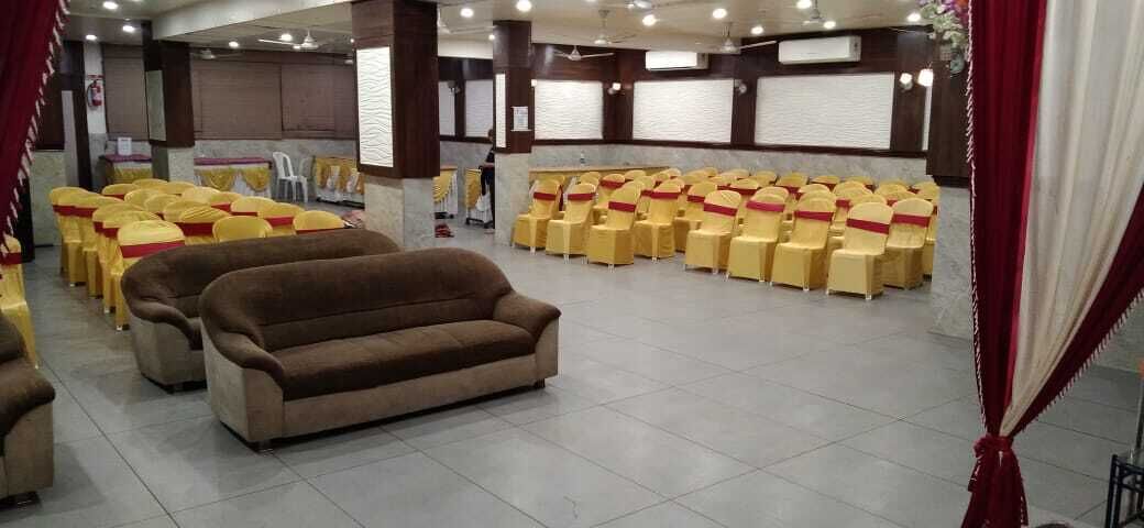 A conference room with rows of yellow chairs, a brown sofa, and a stage area.