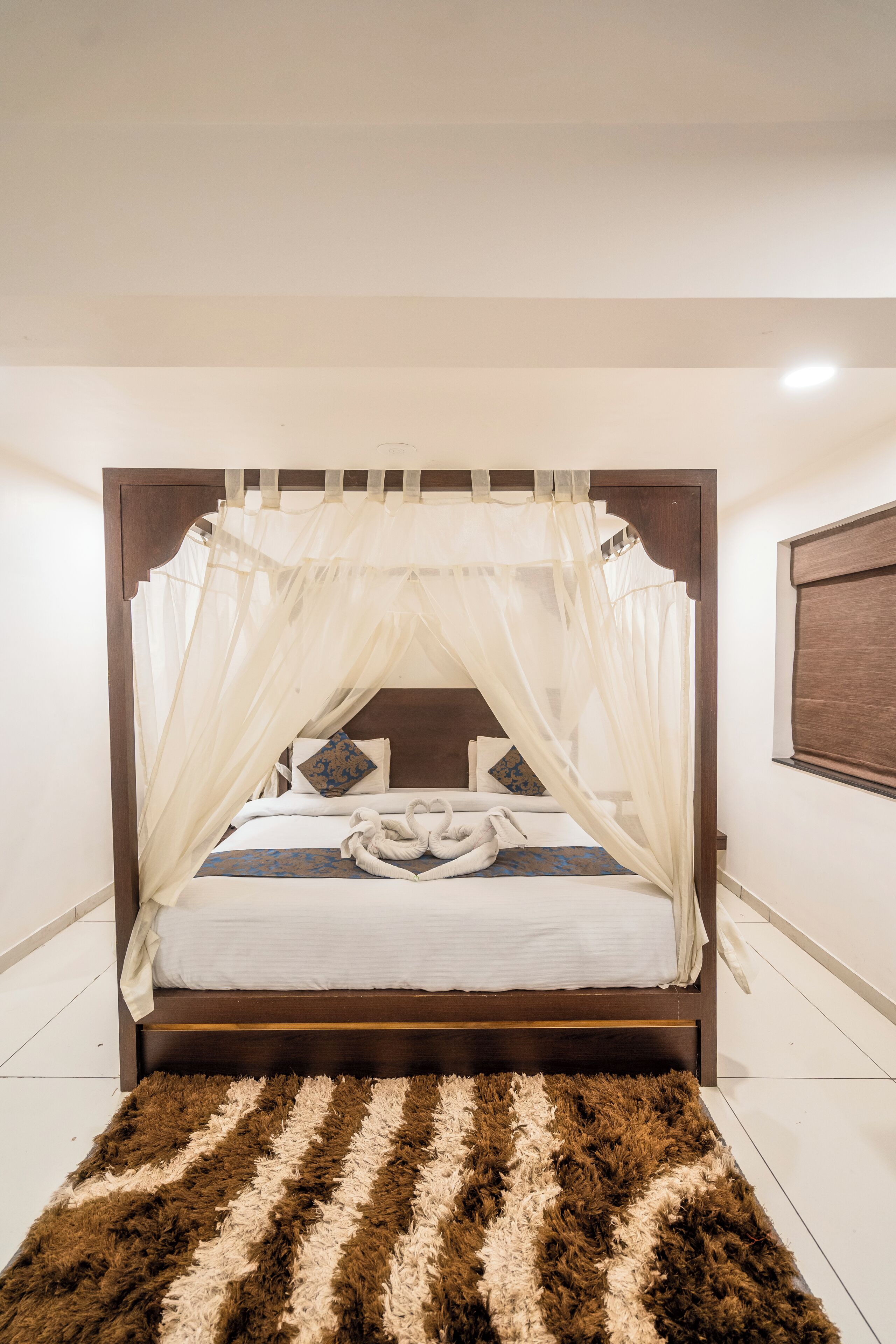 A bedroom with a canopy bed, a fluffy rug, and a wooden headboard.
