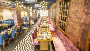 A restaurant with long communal tables, individual booths, and brick walls. - Hotel Bhabha (Rajkot)