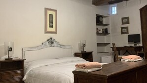 Un dormitorio con cama, mesitas de noche, escritorio y una silla.