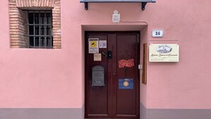 Un edificio rosa con una puerta marrón, una ventana pequeña y un letrero que indica el número 36.