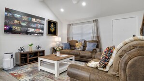 Een woonkamer met een bank, salontafel en een flatscreen televisie waarop een selectie films wordt weergegeven.