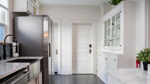 Una cocina moderna con electrodomésticos de acero inoxidable, armarios blancos y piso de madera.
