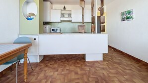 A compact kitchen with a white countertop, a microwave, and a hanging light fixture.