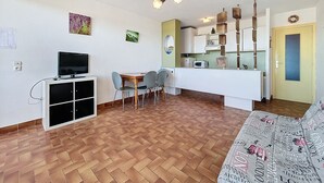 A compact living space with a dining area, kitchenette, and a TV on a cabinet.