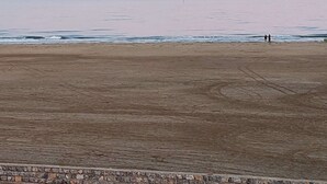 A beach with a stone border and a calm sea.