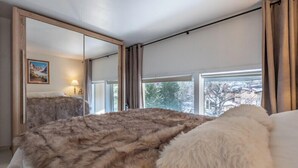 Een slaapkamer met een groot bed, een spiegel en een raam met gordijnen.