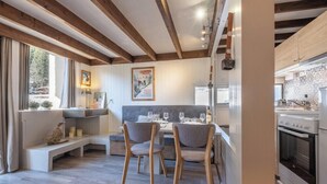 Een moderne keuken met witte kastjes, een ingebouwde oven en een eethoek met een bank en stoelen.