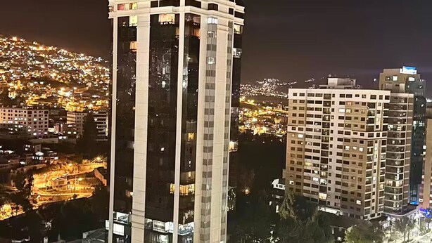 A high-rise building with a modern architectural design, featuring a prominent central tower and multiple balconies.