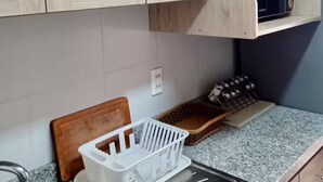 A kitchen with wooden cabinets, a granite countertop, a sink, and a microwave.