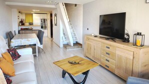 Un salon moderne avec un canapé, une table basse, un téléviseur et un meuble en bois.