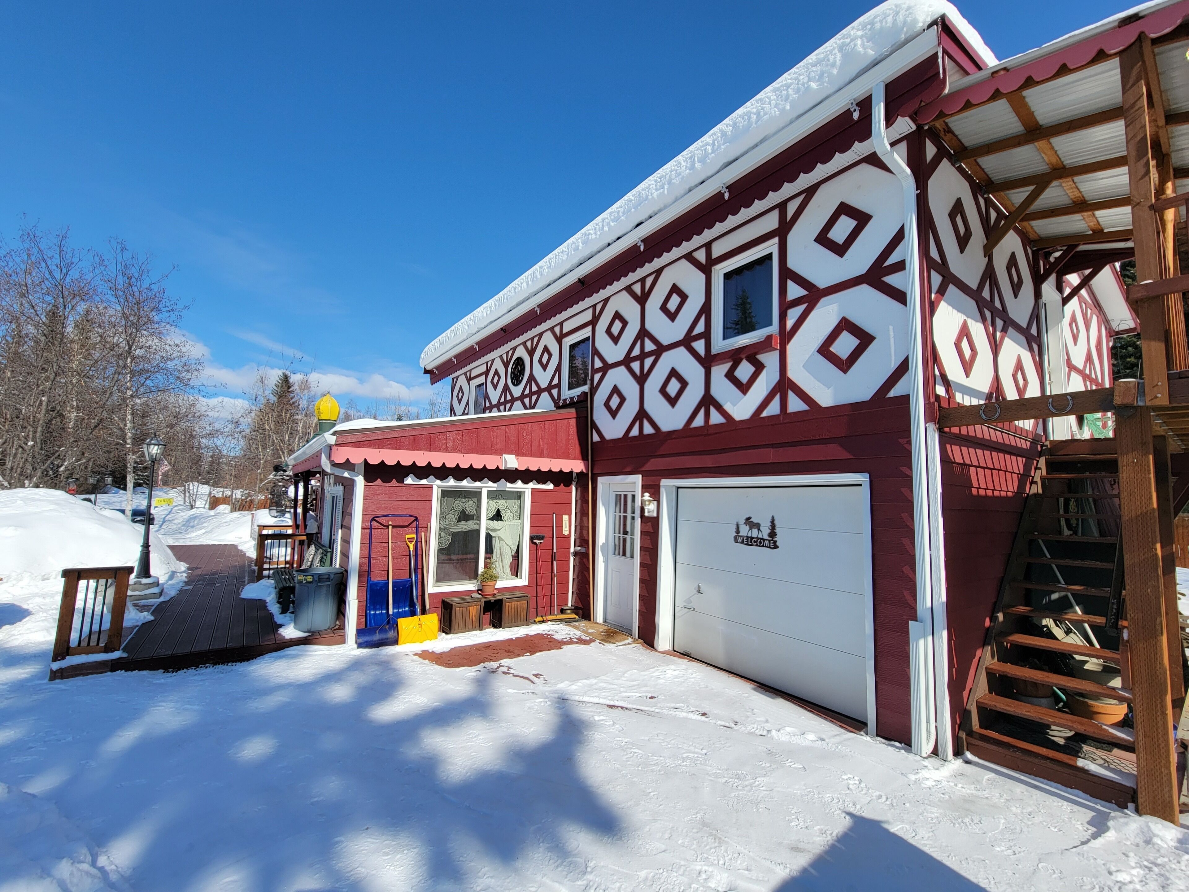A snow-covered building with a garage and a covered porch area.