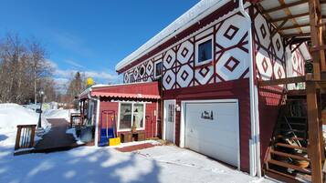 A snow-covered building with a garage and a covered porch area.