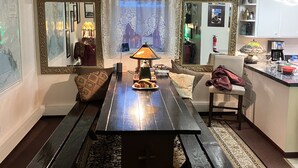 Un soggiorno con un tavolino in legno, un divano, una poltrona e un angolo cottura con pensili e un lavello.