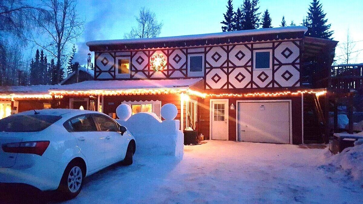 Um edifício de dois andares com uma entrada coberta de neve e um carro estacionado na frente.