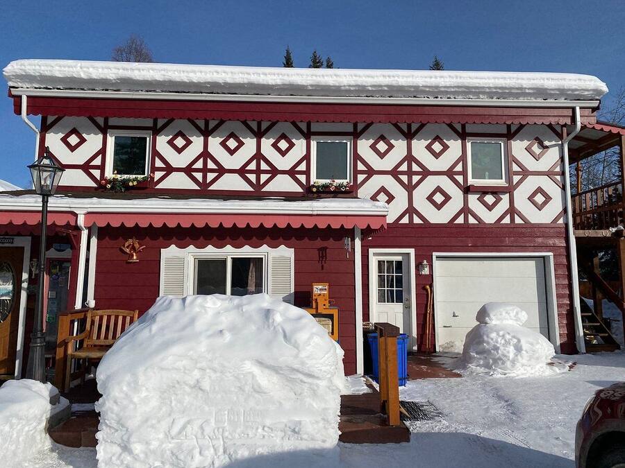A two-story building with a symmetrical facade, a garage, and a snow-covered ground.