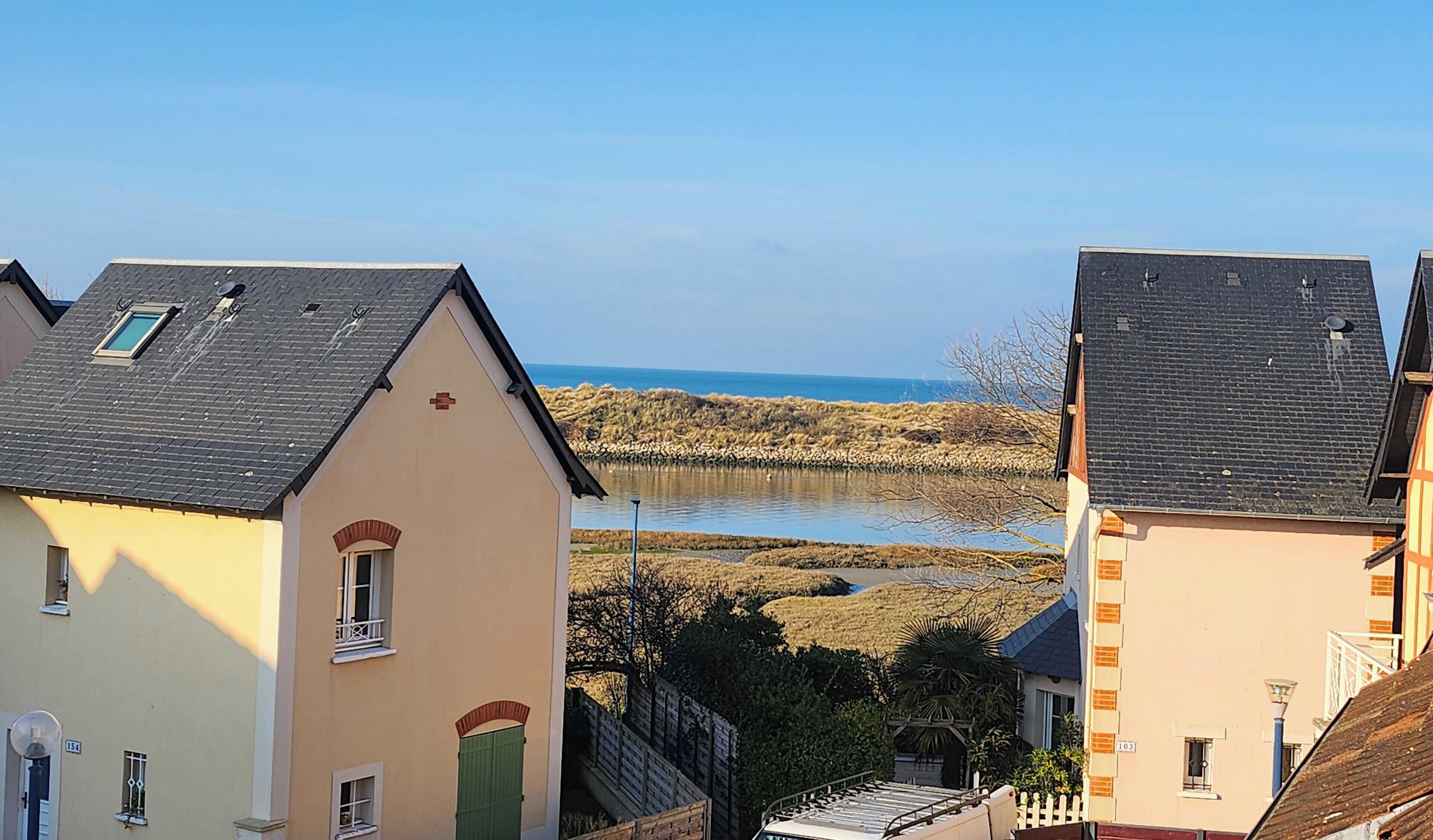 A coastal residential area with houses featuring pitched roofs and a view of the sea.