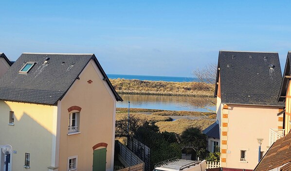 A coastal residential area with houses featuring pitched roofs and a view of the sea.
