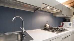 Eine moderne Küche mit Spüle aus Edelstahl, einem Gasherd und weißen Schränken.