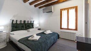 Ein Schlafzimmer mit Bett, Nachttisch, Kommode, Fenster und Klimaanlage.