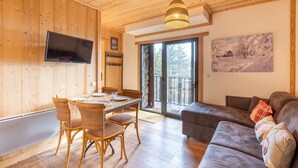 A wooden interior with a dining area, a sofa, and a TV mounted on the wall.