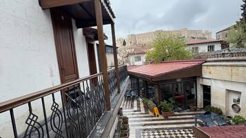 A courtyard with a checkered floor, potted plants, and a view of a historic building in the background.