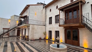 A courtyard with a checkered floor, a fountain, and buildings with balconies and stairs. - ALİ RIZA BEY KONAĞI (Gaziantep)
