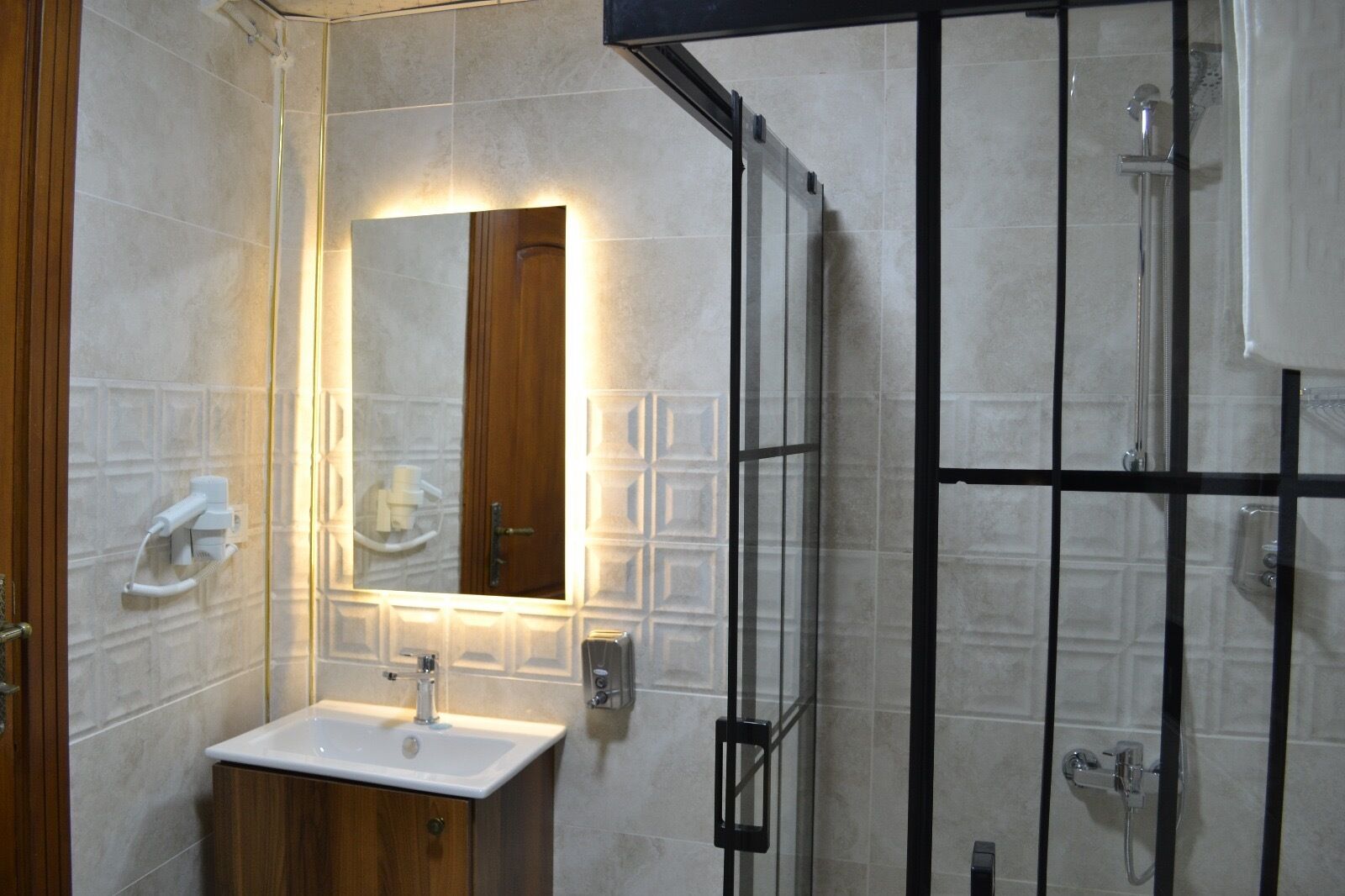 Un baño con tocador de madera, un espejo, cabina de ducha y perchero.