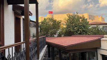 A courtyard with a checkered floor, outdoor seating, and a view of a historic building with a flag.