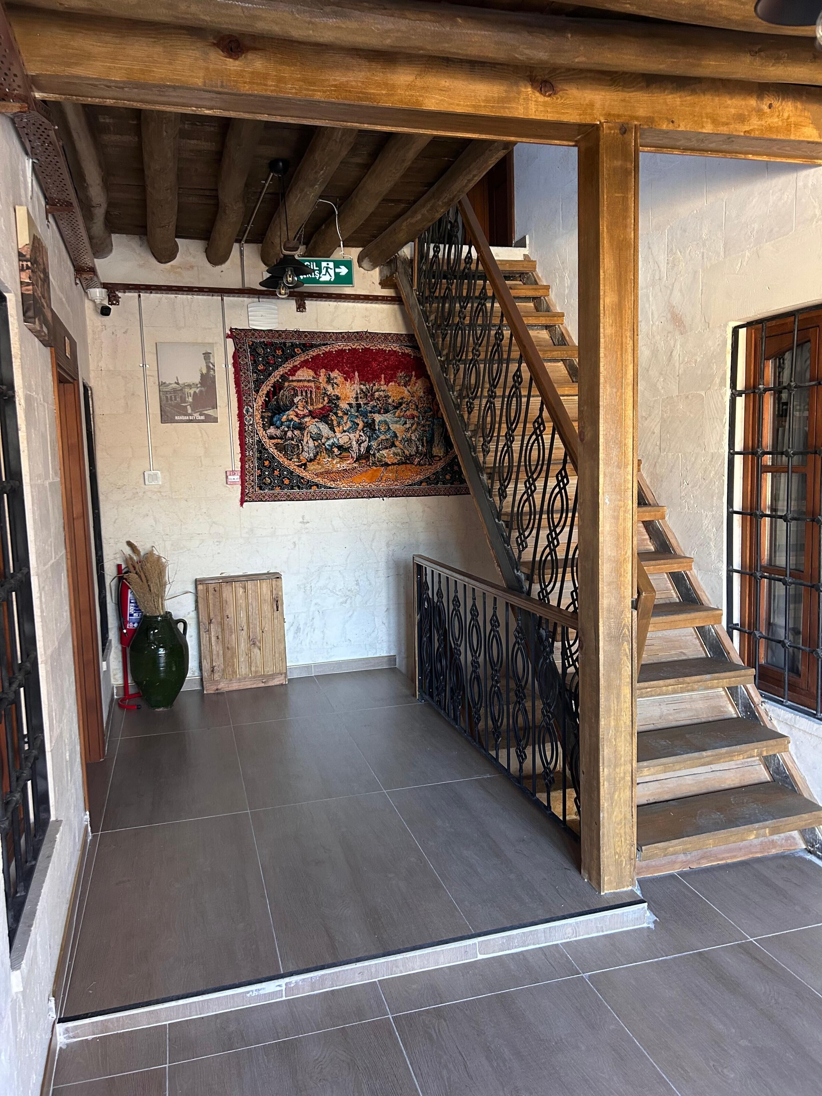 Una escalera con barandillas de madera y piso de baldosas que sube a un nivel superior.