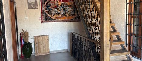 Una escalera con barandillas de madera y piso de baldosas que sube a un nivel superior.